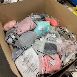 Open cardboard box filled with colorful sealed plastic bags of clothing bundles in a warehouse setting.